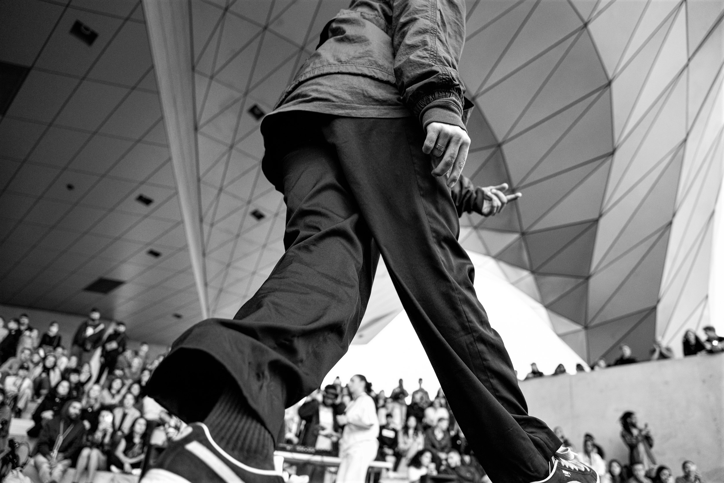 Une danseuse lors d'un battle entouré d'un public sous une architecture